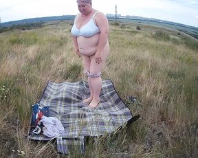 fat woman masturbates with a toy in the field